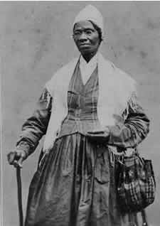 Sojourner Truth, three-quarter length portrait, standing, wearing spectacles, shawl, and peaked cap, right hand resting on cane