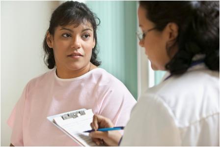 Female health provider with clipboard speaks to female patient