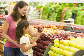 Woman and Little Girl Standing in a Produce Section Near Apples