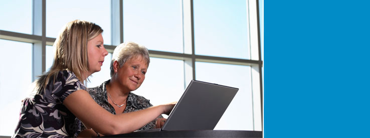 woman helping another on the computer