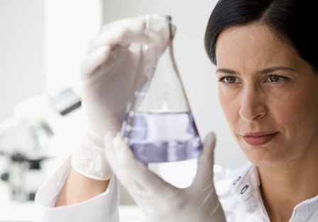 Female researcher examines beaker with fluid