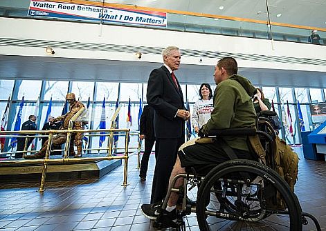 Secretary of the Navy (SECNAV) the Honorable Ray Mabus speaks with Cpl. Joshua Lopez, a wounded warrior at the Walter Reed National Military Medical Center. Secretary Mabus spoke with Sailors and Marines after presenting the Department of the Navy's highest award for civilians, the Navy Distinguished Public Service Medal, to U.S. Congressman C.W. 