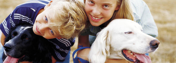 boy and girl each hugging a dog and smiling 