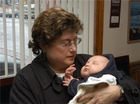 A woman cradles her baby grandchild. - Click to enlarge in new window.