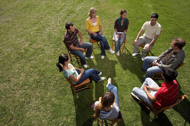 Young people sitting in a circle on the grass.