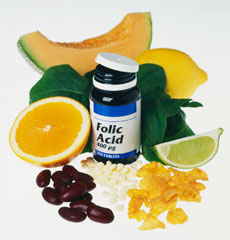 Bottle of folic acid surrounded by various citrus fruits.