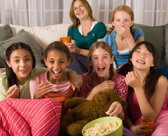 A group of girls wearing pajamas and eating popcorn.