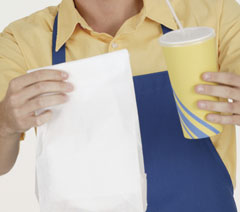 A man holding a bag of fast food and a soda.