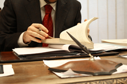 Man in Suit Reviewing Book & Files at Desk