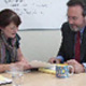 Woman and man talking over desk.