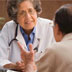 A health professional speaks with a patient and points to a clipboard