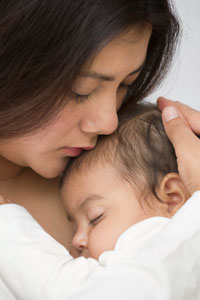 Photograph of a teen mother cuddling her infant.