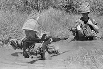 Two male soldiers wading through water in Vietnam