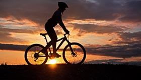 female student riding bike against sunrise