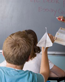 Boy throwing paper airplane in class.