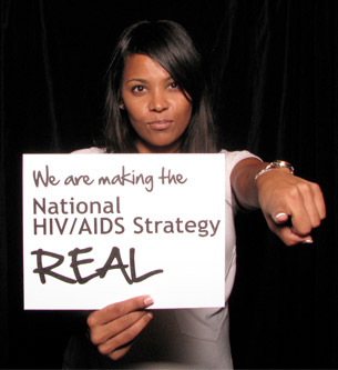 woman holding sign 'Facing AIDS by making the National HIV/AIDS Strategy REAL.'
