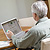 A man holds a pill bottle while looking at his laptop computer.