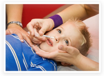 A young boy is getting the nasal spray flu vaccine from his pediatrician