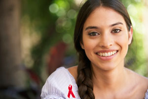 Photograph of a Latina teen girl wearing a red AIDS awareness ribbon on her blouse.