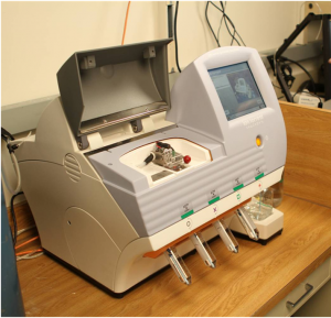 Device on benchtop in lab, featuring open lid for placement of microarray chip and to the right, a read-out screen.