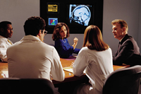 A group of doctors sitting at a table and discussing an X-ray of a brain