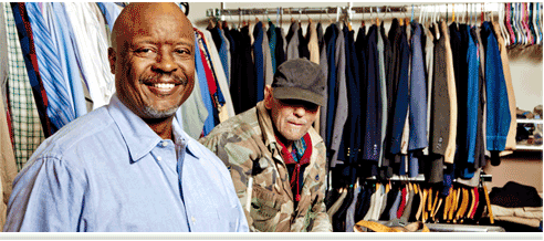 Two men in front of a rack of clothes.