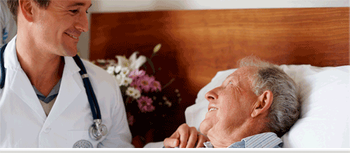 A male medical professional smiling at an elderly patient.