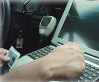 Close-up of individual typing on laptop in a vehicle