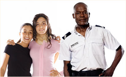 Photograph of a police officer standing with two smiling young women.