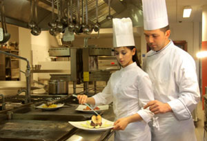 Photograph of a chef instructing an apprentice chef.