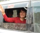 Aung San Suu Kyi waves to supporters from car after election victory.