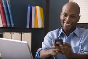 Photograph of a smiling man making a telephone call.
