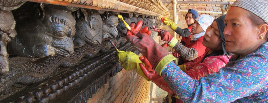 A group of workers cleaning a carved cornice