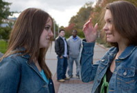 Two girls wearing denim jackets chatting.