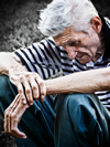 An elderly man is depressed and has his head down