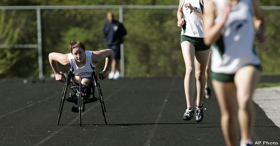 Wheelchair athlete, left, races along side able-bodied high school runners, April 19, 2006 in Rockville, Md. [AP File Photo]