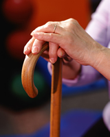 A woman's hands are resting on a cane