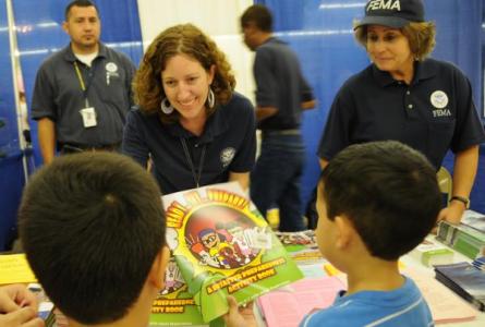 FEMA employees give out coloring books to children at a local health fair.