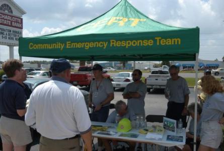 CERT members and other individuals stand around a CERT tent and booth.