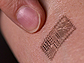 Finger pointing to electronic tattoo on skin