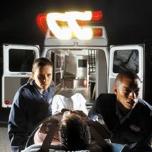 Paramedics wheel a patient out of an ambulance