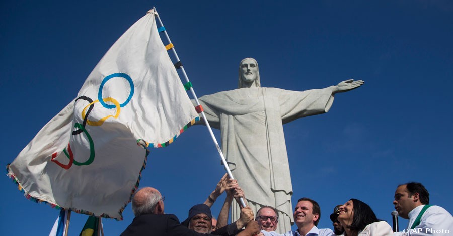 Rio de Janeiro's Mayor Eduardo Paes, third right, Brazilian Olympic Committee president Carlos Arthur Nuzman, center, and representatives from civil society wave the newly arrived Olympic flag in front of the Christ the Redeemer in Rio de Janeiro, Aug. 19, 2012. In 2016, Rio de Janeiro will host the Olympic Games. [AP File Photo]