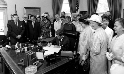 President John F. Kennedy signing the Equal Pay Act of 1963, which prohibits arbitrary discrimination against women in the payment of wages.