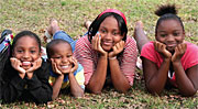 Image of three girls and a boy laying in the lawn smiling