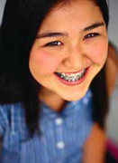 Dark-haired girl with braces smiling.