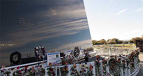 Wreaths and flowers line the Space Mirror Memorial during NASA's Day of Remembrance