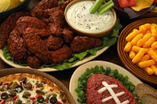 Buffet of traditional Super Bowl food items, platters, and dips. 