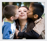 Two kids kissing their mother