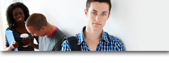 Young student leaning on wall with friends behind