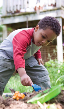 Young boy playing in his yard, digging in the dirt